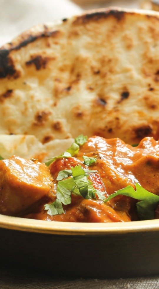 Traditional Indian Curry from Taste of India, Sheerness. Available for delivery and take away Close up of a bowl of curry with naan, garnished with coriander